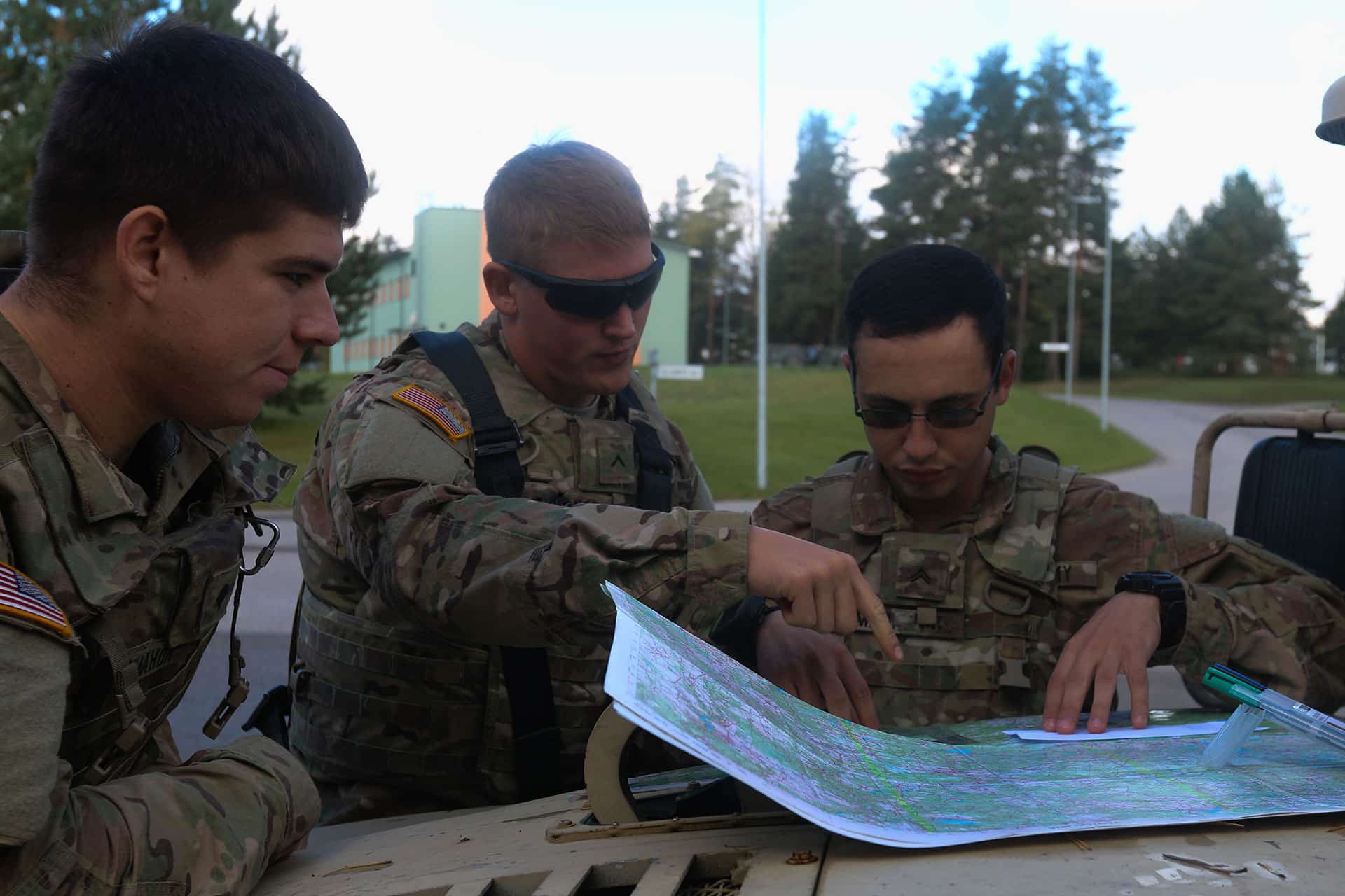 Three soldiers plot a course on a map during Land Navigation trianing