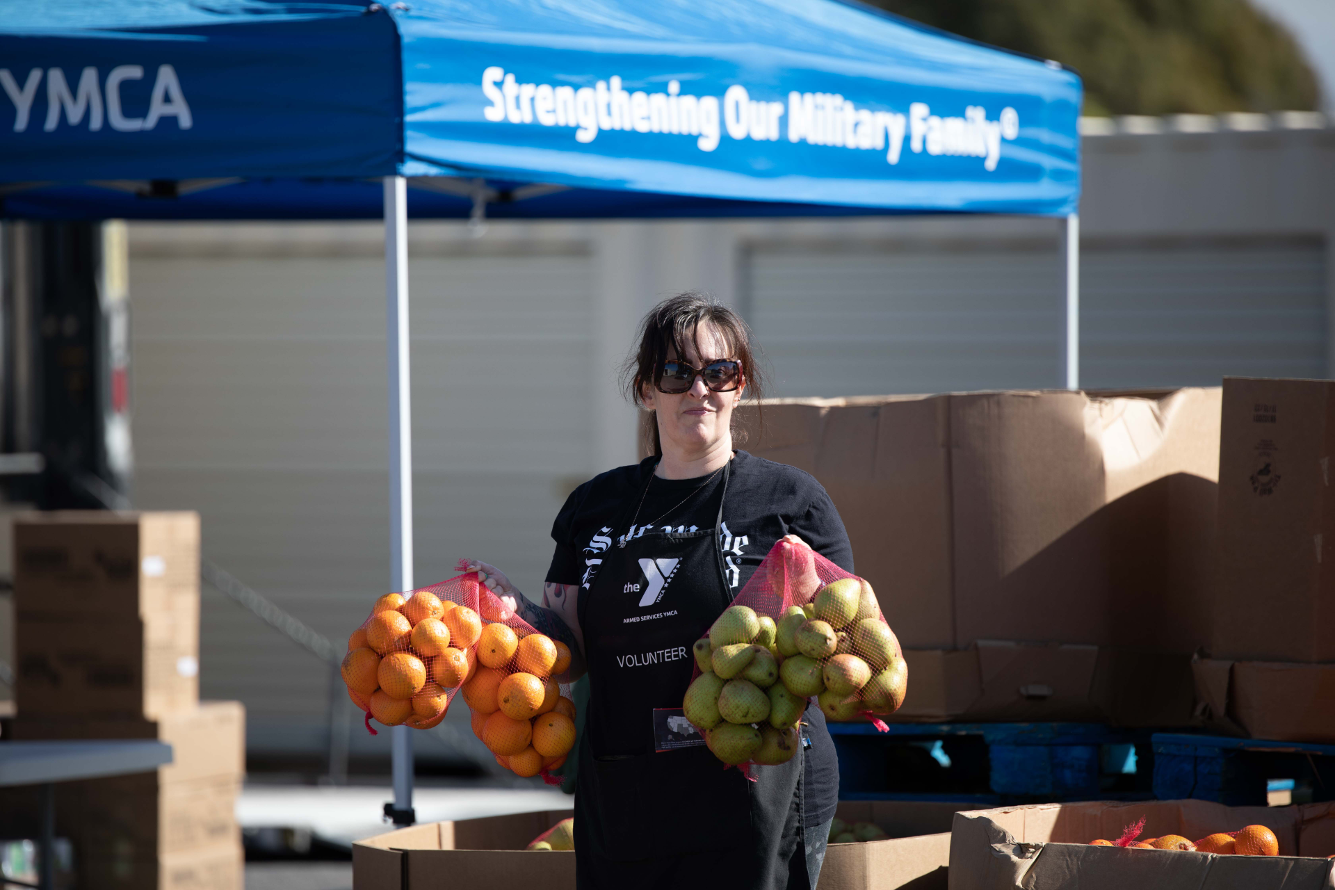 A volunteer holds fresh fruits during a food distribution events at the Armed Services YMCA